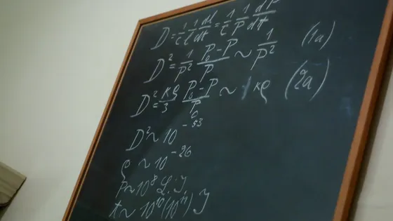A classroom blackboard covered in hand-written mathematical equations