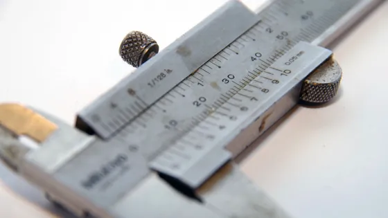 A vernier caliper measuring a small object, with the millimetre scale in focus